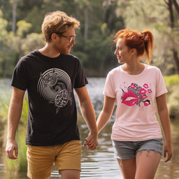 Couple holding hands and walking by a lake. Man wearing black t-shirt with white turtle graphic, women wearing pink t-shirt with pink seven kisses graphic. T-shirt designs by studio bilby.