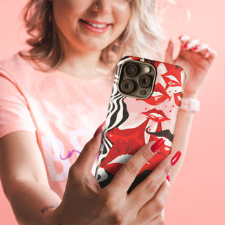 Women wearing pink holding the 'Kissable' tough phone case by Studio Bilby. Background is pale pink to match her clothing.