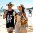 Man and women walking on the beach. Man wearing black t-shirt with white 'Born to Surf' graphic on it by Studio Bilby. Women wearing a cream coloured dress, holding the 'Ocean Orange' tough phone and the 'Sunflower' tote bag by Studio Bilby.